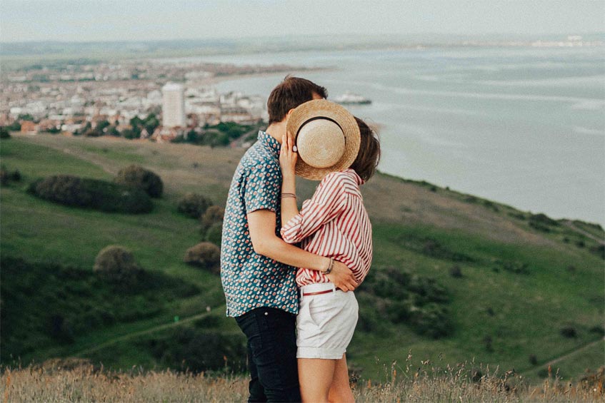 Man and woman hugging behind a hat 